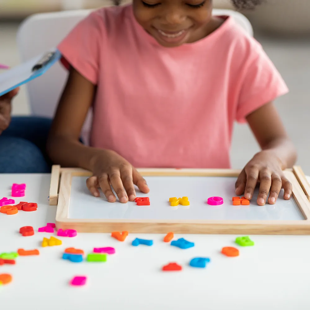 A child using magnetized colorful letters to spell HOME at a Little Sprouts daycare