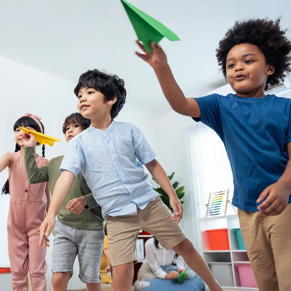 Children launching colorful paper airplanes in a Little Sprouts daycare