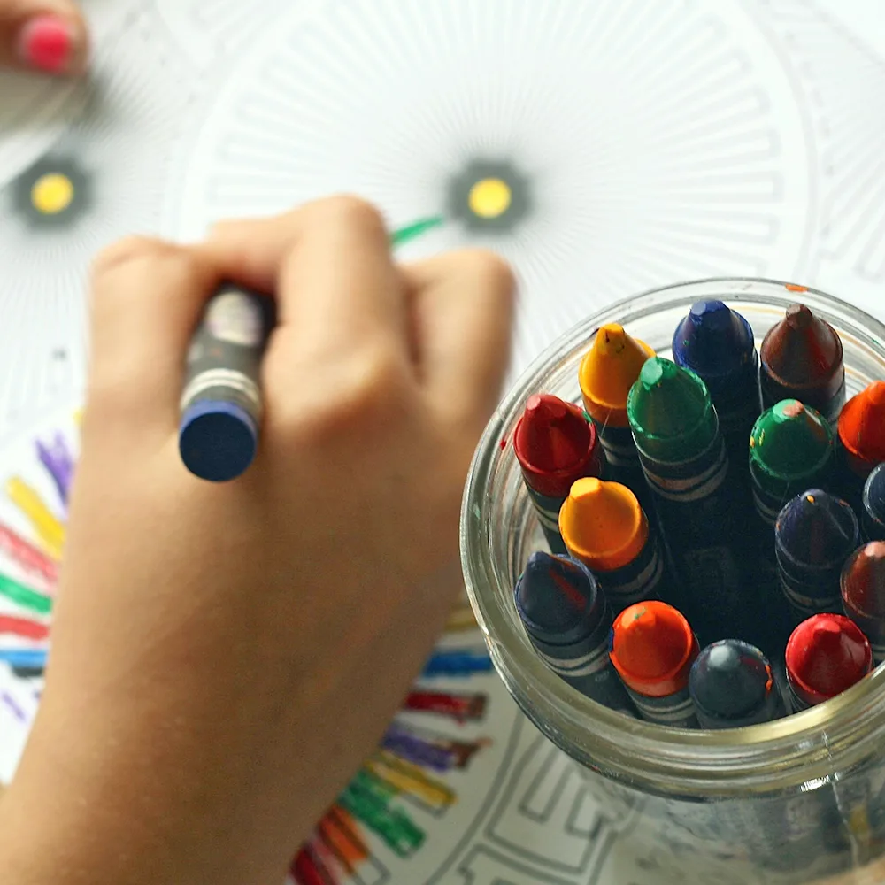 A child using a blue crayon to color a wheel at a Little Sprouts daycare