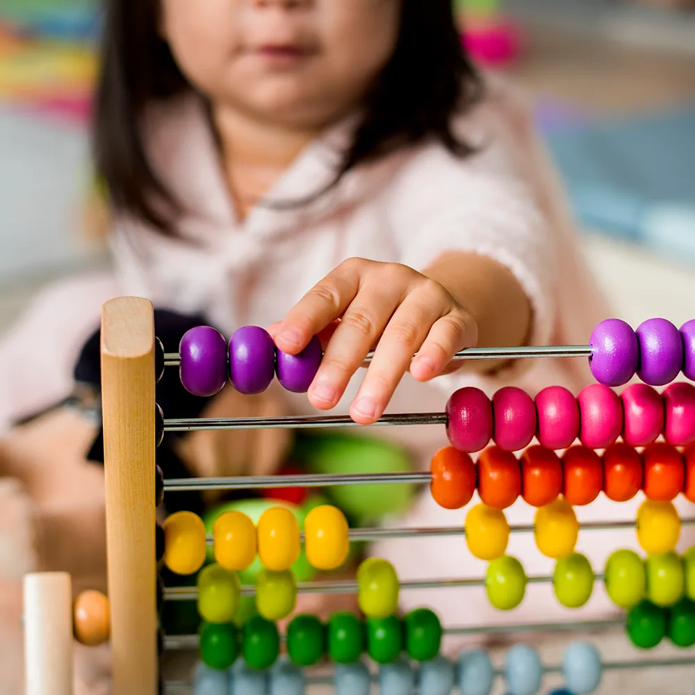 A child working with beads on an abacus at Little Sprouts daycare