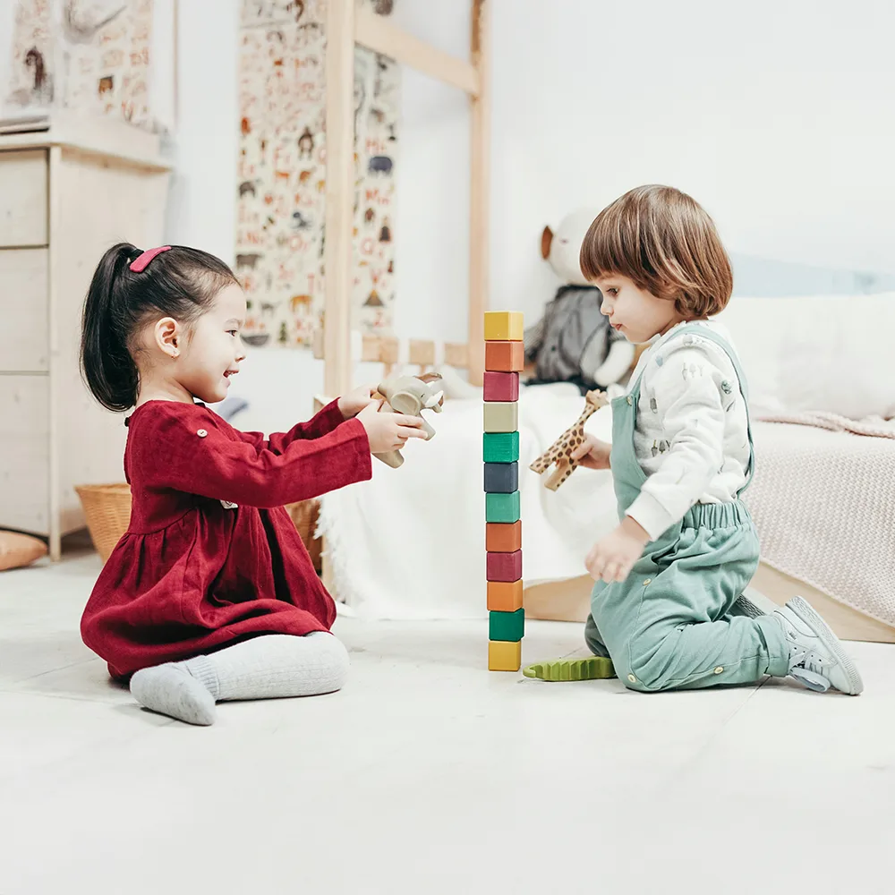 Two children stacking colorful blocks on a floor at Little Sprouts daycare