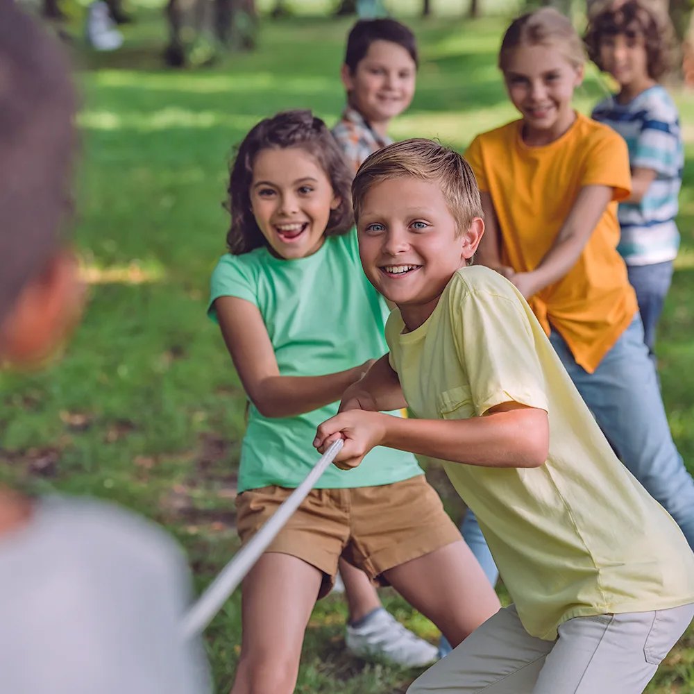 A group of children playing tug of war during summer camp at a Little Sprouts daycare