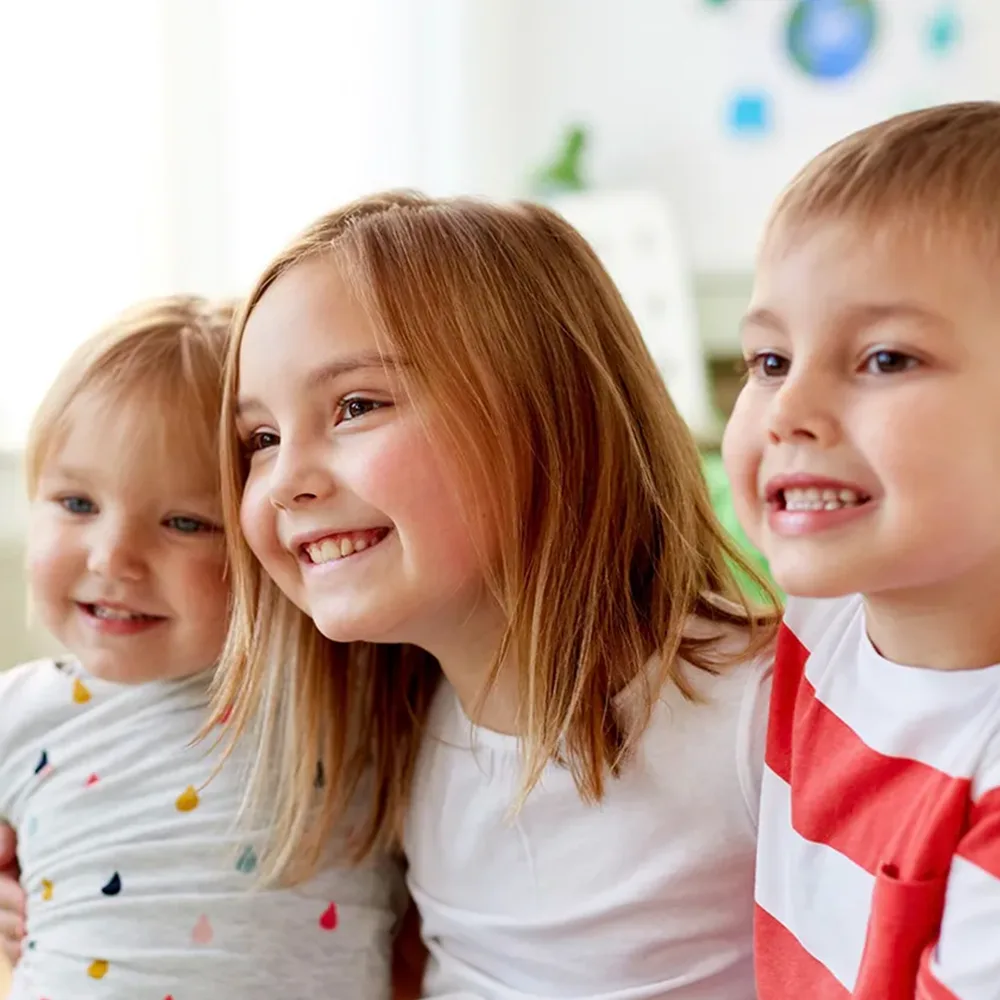 Three children hugging and smiling at a Little Sprouts daycare
