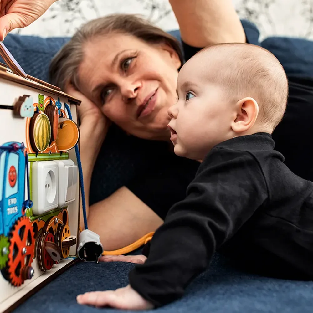 A teacher showing an infant a play box on the floor at a Little Sprouts daycare