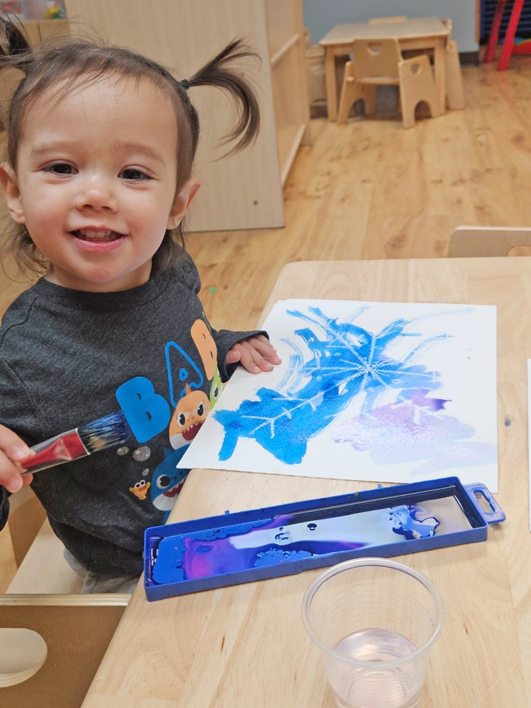 Child coloring with blue crayon at a Little Sprouts daycare.