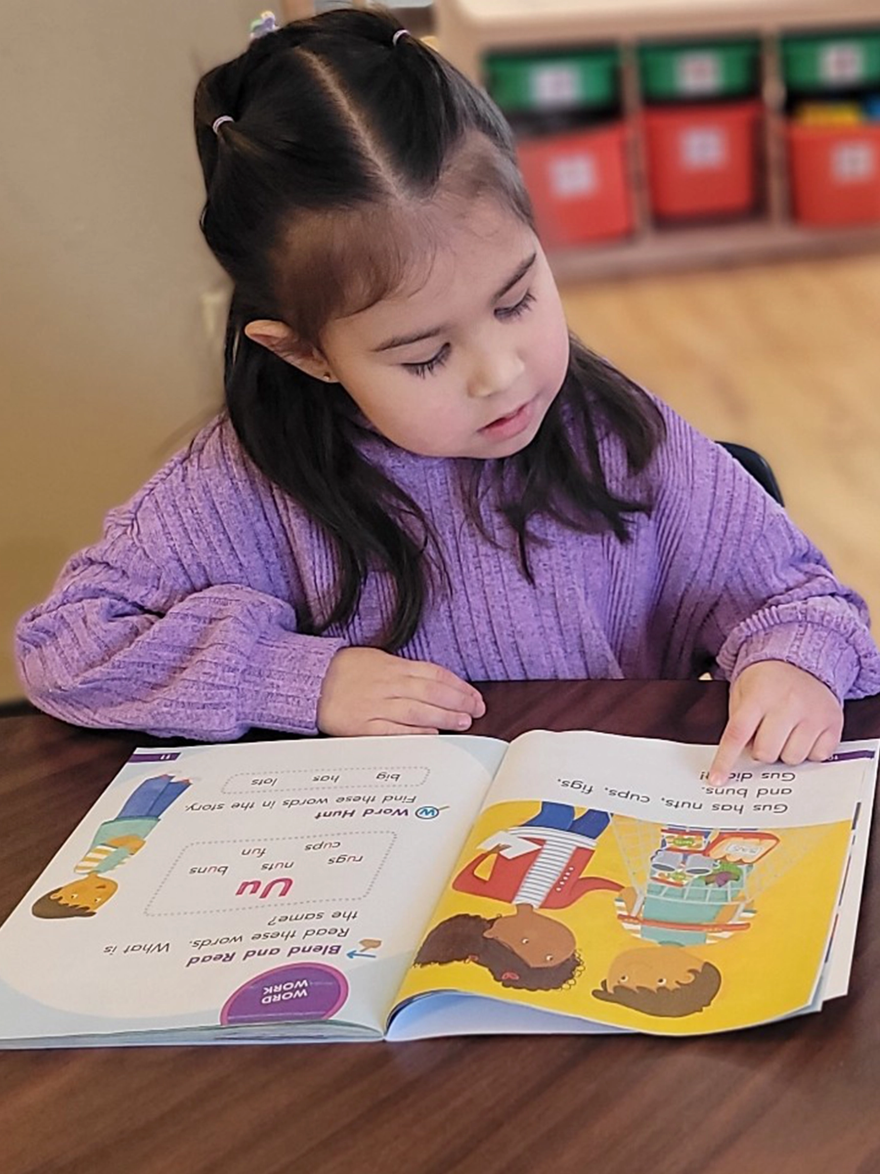 A child in purple reading a book at Little Sprouts daycare.