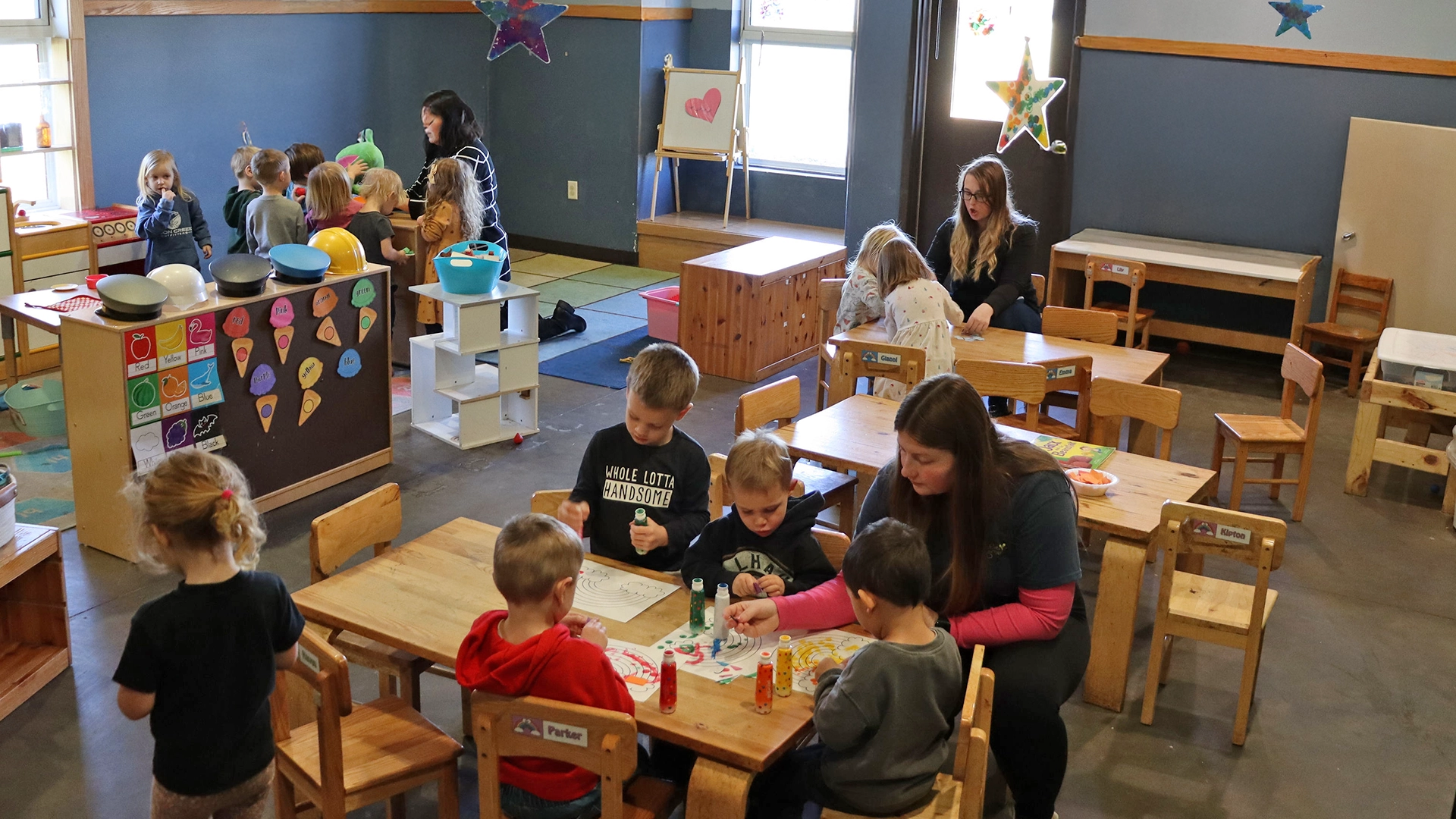 Children at tables with teachers learning at a Little Sprouts daycare