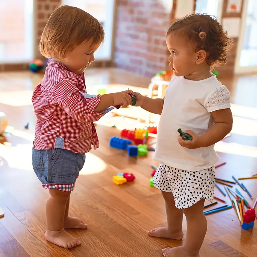 Two toddlers sharing toys at a Little Sprouts daycare